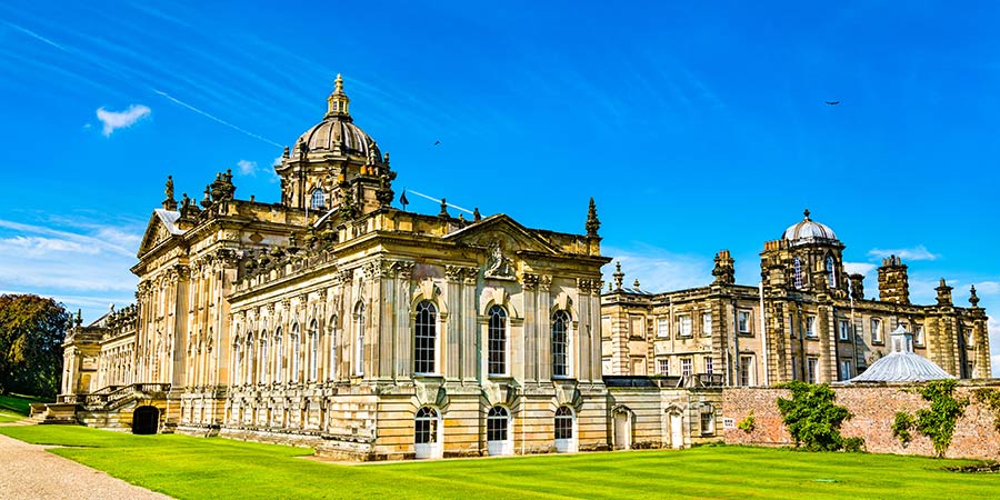 View of large stately home with intricate architectural details on the stone facade. 