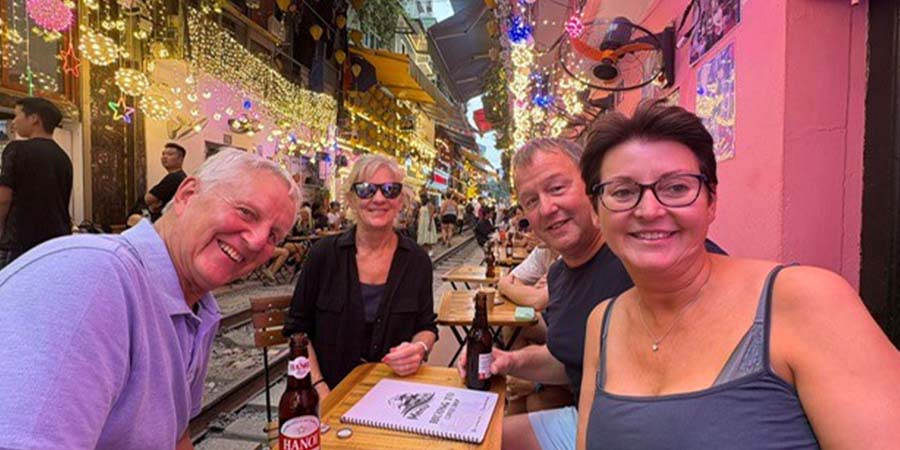 Four friends smiling round a table at a café in Hanoi’s Old Quarter, Vietnam. 